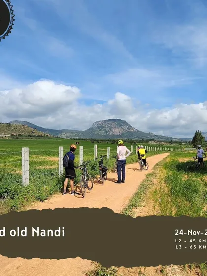 The 'Good old Nandi' tour is a classic for a reason. This image shows riders on a trail through green fields with the iconic Nandi Hills in the background.
