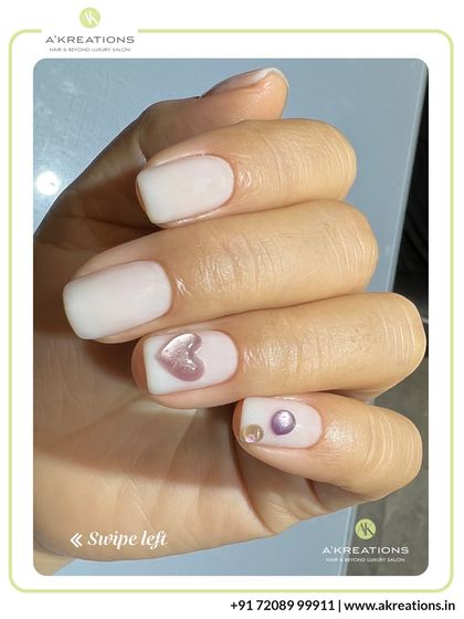 A chic and minimalist design on short nails, featuring a soft white base with a raised 3D heart accent and delicate pearl and gem placements.
