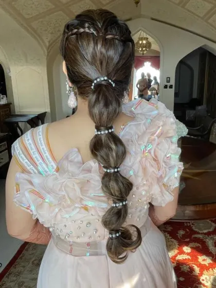An indoor shot of the intricate heart braid and pearl bubble ponytail.
