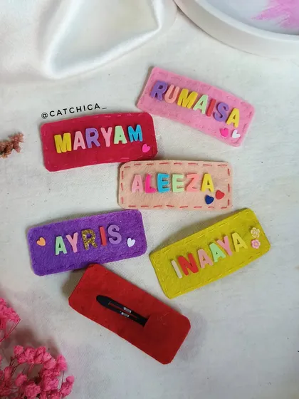 Showing the front and back of our felt name clips. You can see the neat stitching and the secure snap clip on the back, making them durable and easy to use.