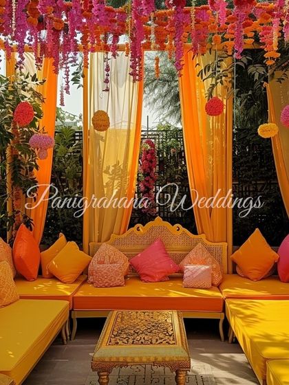 A cozy and colorful Mehendi seating area. We used bright orange and pink custom cushions, along with a ceiling of marigold strings, to create a traditional yet chic lounge space.