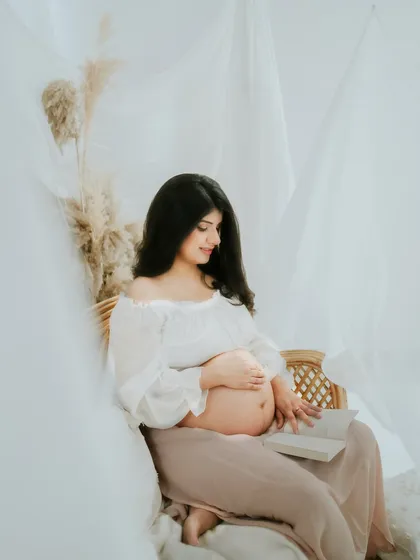 A peaceful moment captured in the studio. Here, the expecting mother is seen reading, adding a personal and serene touch to her maternity photoshoot.