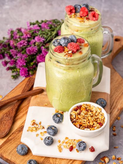 Healthy green smoothies styled with fresh berries and granola. This shot is perfect for wellness brands or cafes wanting to highlight their fresh, nutritious offerings.
