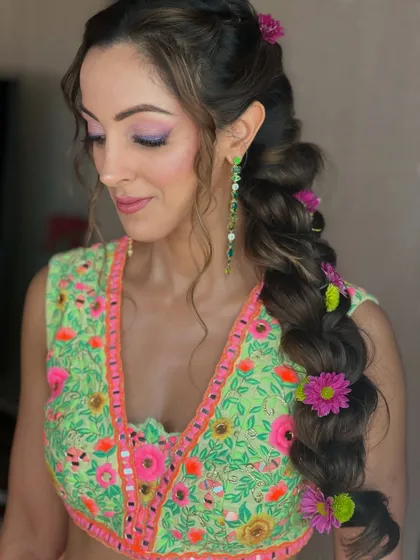 The client looking stunning with her mehendi look. The playful hairstyle is perfect for the festive and joyful atmosphere of the event.