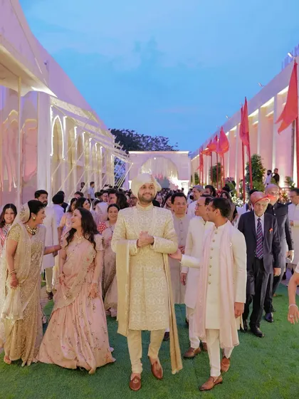 Shivam walks with his family to the wedding ceremony. The line of smiling faces and the beautiful twilight sky create a sense of joyful procession and family unity.