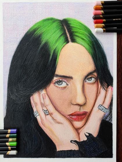 The full view of the Billie Eilish drawing, framed by the colored pencils used to create it.