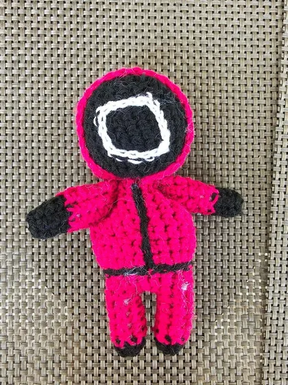 A flat-lay photo of the Squid Game guard doll.