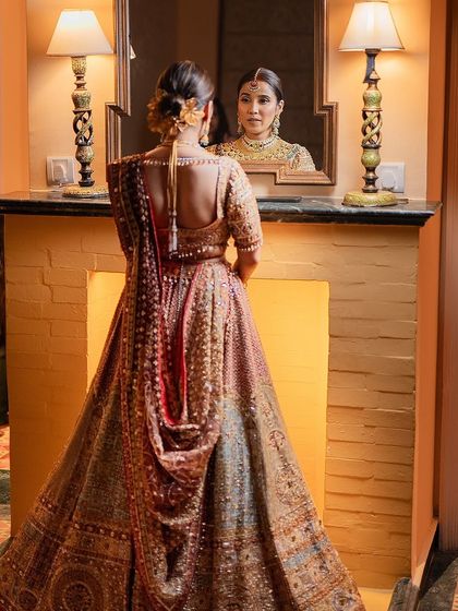 A look in the mirror before the reception. The bride's reflection captures the beauty of her heritage-inspired ensemble and the intricate details of her hair and jewelry.
