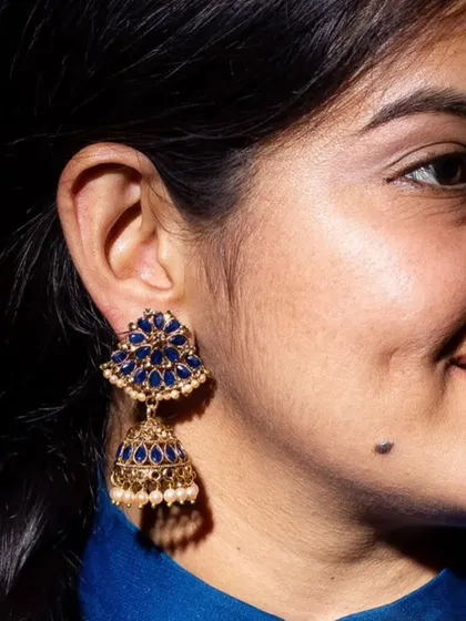 That blue in a Bindhani jhumka. This piece combines deep blue stones with a golden base and pearl details, creating a rich and elegant look.