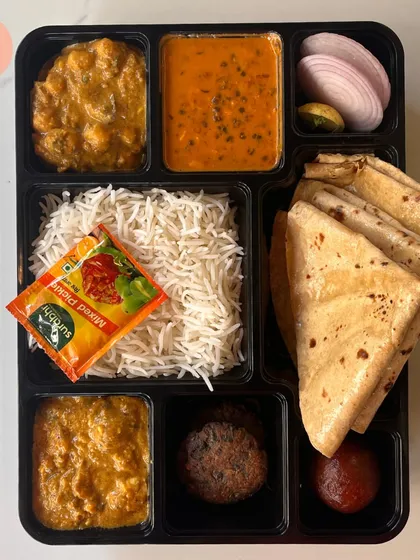 Take a look at our premium North Indian meal box. This thali features multiple vegetable preparations, dal makhani, fluffy basmati rice, soft rotis, a kebab, and a gulab jamun for dessert. It's a complete, wholesome meal packed hygienically for any occasion.