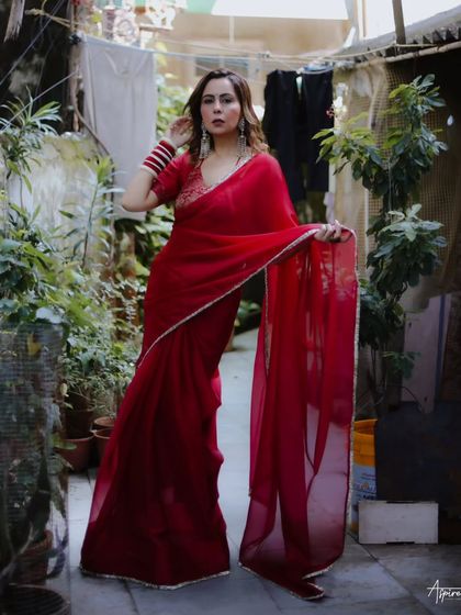 Taking the studio outside. This shot from our urban elegance series places the vibrant red saree against a rustic, everyday backdrop, creating a beautiful and striking contrast.