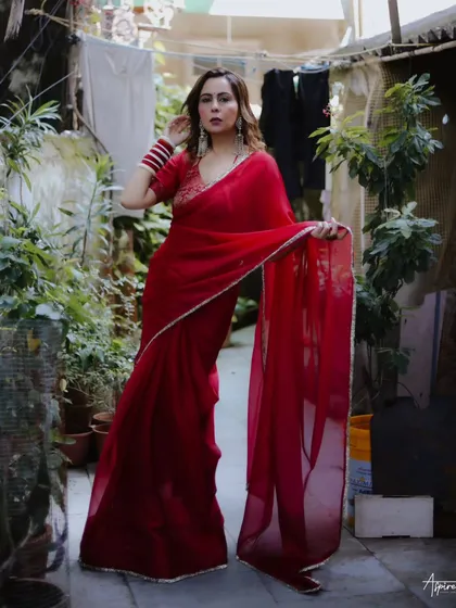 Taking the studio outside. This shot from our urban elegance series places the vibrant red saree against a rustic, everyday backdrop, creating a beautiful and striking contrast.