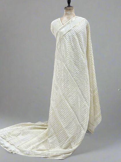 A mannequin draped in an elegant off-white saree with silver stripes.