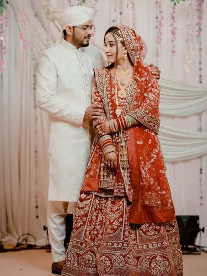 A beautiful couple portrait. My bride looks elegant and poised in her red embroidered lehenga, with makeup that enhances her features without overpowering them.