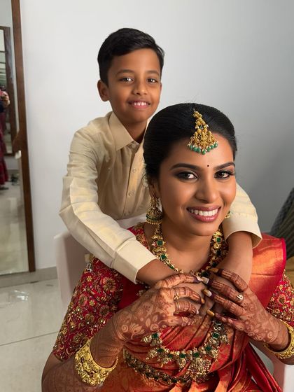 A heartwarming moment between my beautiful bride Abi and her son. Her gorgeous Muhurtham look features a radiant smile, glowing skin, and traditional gold jewellery that perfectly matches her red silk saree.