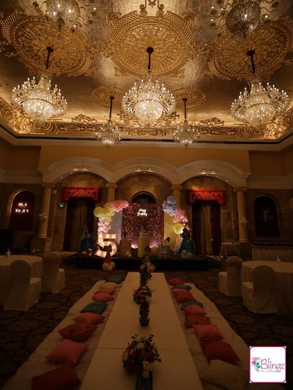 A wide-angle view of a magnificent ballroom transformed for a Disney Princess party. The grand chandeliers of the venue complement the royal theme, with low seating for the little guests creating a unique and kid-friendly atmosphere.