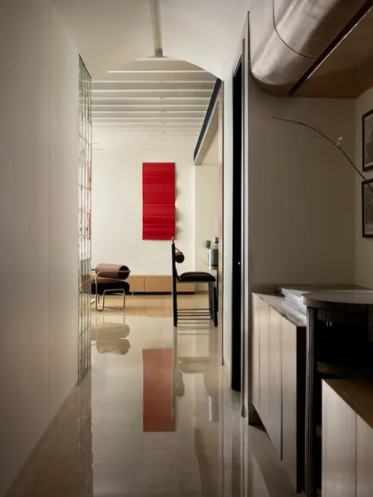 The passage from the bedroom to the living room is designed like a gallery. The polished marble floor reflects the bold red metal art, creating a dynamic and artistic transition between spaces.