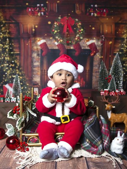 Another adorable shot of the little Santa, capturing his surprised expression as he holds a Christmas bauble.