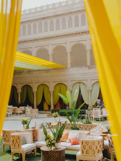 A peek through bright yellow curtains into the Haldi courtyard. The design used layers of color and texture to create a dynamic and engaging space, with comfortable seating areas for guests to relax and mingle.