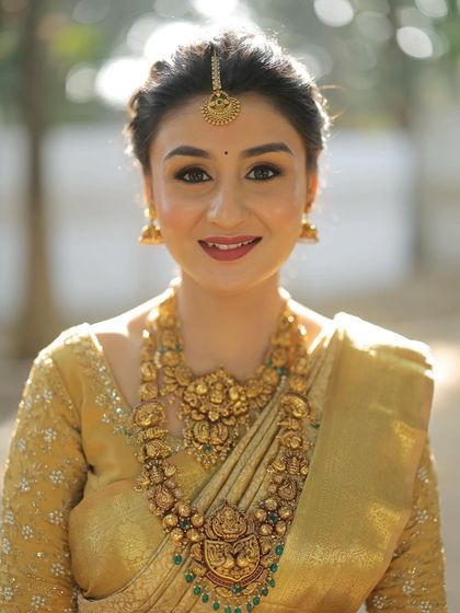 A close-up of my gorgeous South Indian bride. Her makeup features a flawless base, defined eyes, and a warm lip color that perfectly complements her golden Kanjeevaram saree and antique temple jewellery.