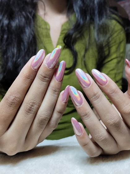 Make a statement with these stunning holographic chrome nails. The light-reflecting powder creates a mesmerizing effect on these long, almond-shaped extensions, shifting colors with every movement.