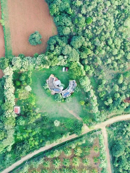 An aerial view of a farmhouse project that I designed to live in harmony with its surroundings. The unique C-shaped structure wraps around a central courtyard, creating a private oasis that is completely integrated with the lush green landscape.