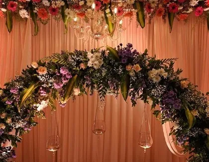 A close-up of the floral arch from a classic reception stage. I used a mix of fresh flowers and hanging glass candle holders to add detail and warmth to the design.