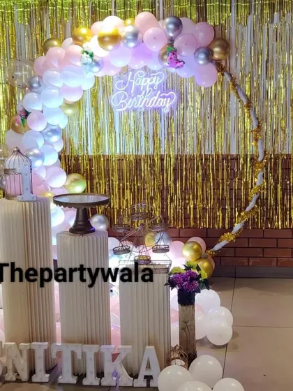 A beautiful ring decoration with a gold shimmer backdrop. The pink, white, and silver balloons look very glamorous against the shiny curtain.