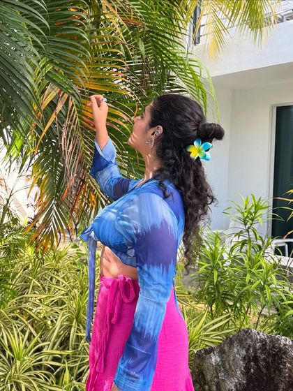 Admiring the tropical plants. This shot adds a touch of nature and serenity to the vacation look.