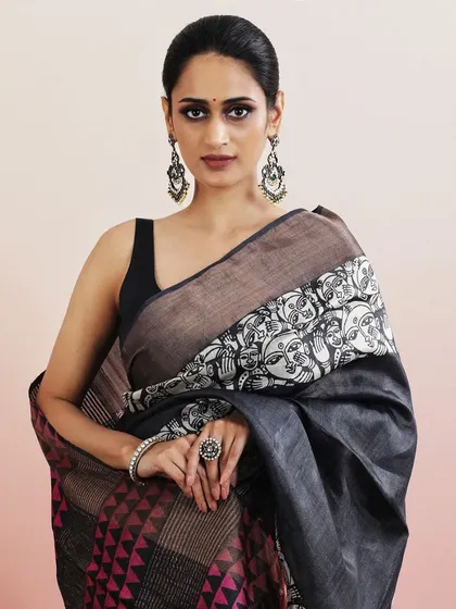 A contemporary saree with a bold, graphic print of faces, contrasted with pink geometric patterns.