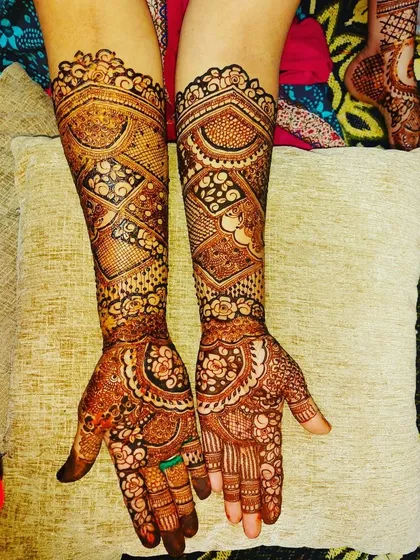 This is a very intricate and symmetrical design that extends well up the forearm. It's filled with detailed patterns, leaving very little negative space for a truly grand bridal look.
