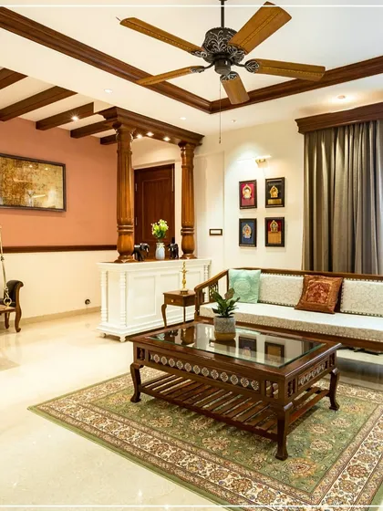 A Kerala-inspired living room with a traditional wooden sofa, carved coffee table, and exposed ceiling beams, creating a warm and authentic atmosphere.