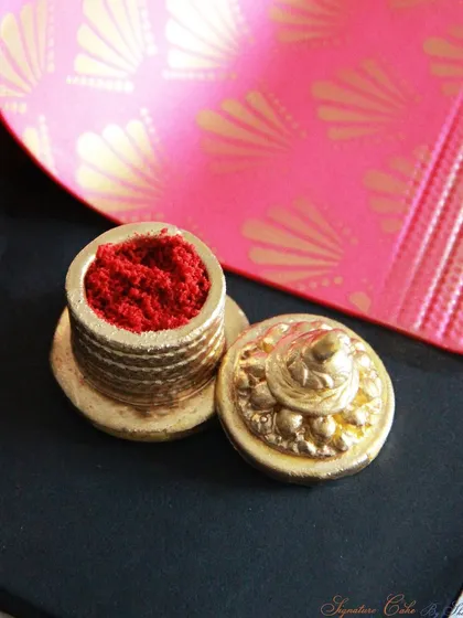 A close-up of the edible sindoor box and lid, part of the stunning Saree Cake. The details are handcrafted from fondant and painted gold.