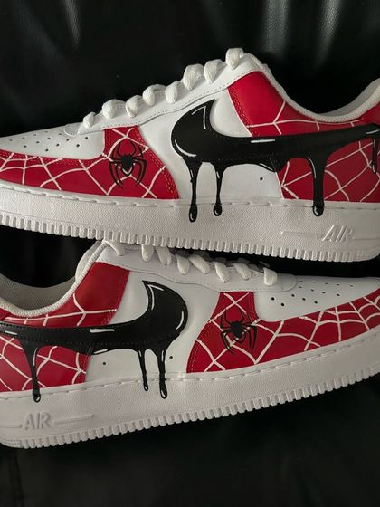 A custom Nike Air Force 1 with a Spiderman theme, featuring a web pattern and a black venom-like drip over the swoosh.