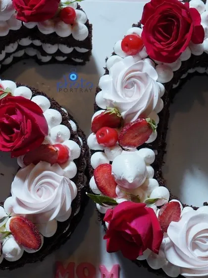 A close up of the beautiful number "60" cake, decorated with fresh roses, strawberries, and cream.