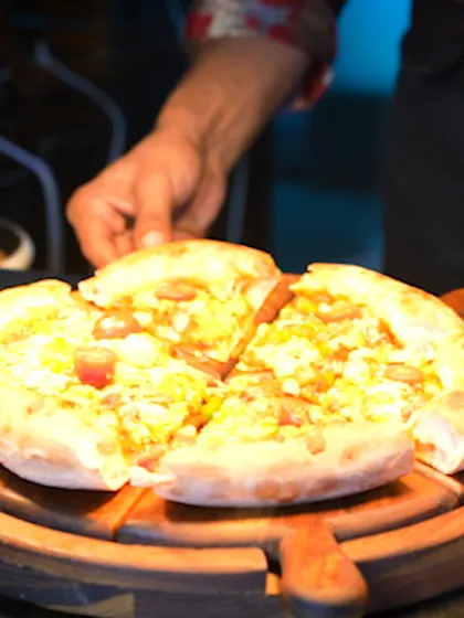 A freshly baked pizza being served, showcasing the delicious, cheesy goodness from our live pizzeria station.