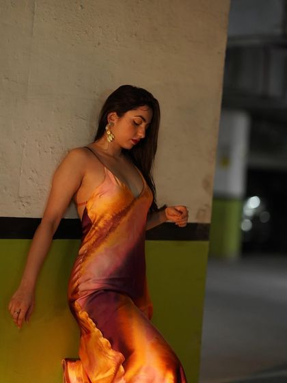 A close-up, thoughtful pose in the satin dress, highlighting the fabric and colors.