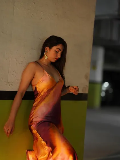 A close-up, thoughtful pose in the satin dress, highlighting the fabric and colors.