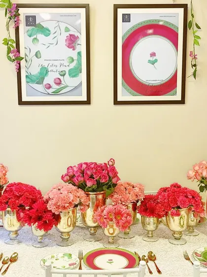A detailed look at a tablescape for KIKA's Lotus Collection launch, featuring a beautiful arrangement of pink and red carnations in gold vases. The table setting coordinates perfectly with the brand's pink and green dinnerware, creating a cohesive and elegant presentation.