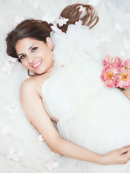 A dreamy, ethereal portrait from above, with the mother-to-be lying in a sea of soft tulle and delicate flowers. This style creates a truly angelic and serene image, focusing on peaceful anticipation.