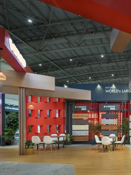 This 220 sq.m exhibition space for Virgo features a striking interplay of materials and volumes. A vibrant red lattice wall serves as a focal point, complemented by wood-clad structures and defined seating areas for visitor discussions.