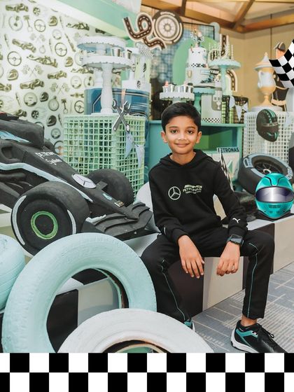The birthday boy, Vihaan, looking cool in his Petronas gear, seated next to a custom-built F1 car prop. This is the ultimate photo op for a young racing fan.