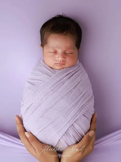 So small and precious. This classic swaddle pose, held gently in loving hands, emphasizes the baby's tininess and the protective love that surrounds them. The lavender tones add a soft, dreamy quality.