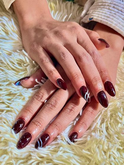 Another look at the deep red nails with a modern white line art accent. The almond shape of the nails adds to the elegance of the design.