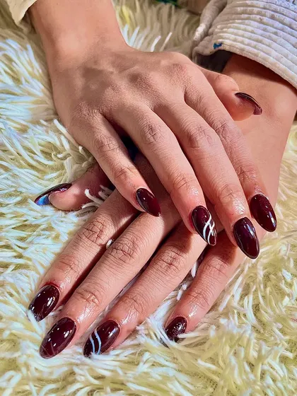 Another look at the deep red nails with a modern white line art accent. The almond shape of the nails adds to the elegance of the design.