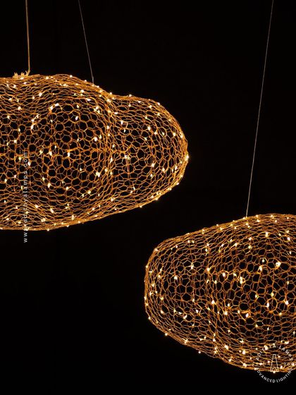 We call this piece the 'Clouds of Abundance'. It is crafted from a delicate honeycomb of intertwining gold wires embedded with tiny LED lights, creating the magical illusion of a glowing cloud. It's a truly enchanting centerpiece for any room.