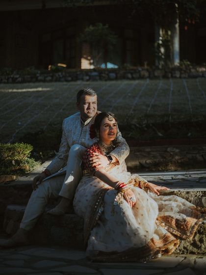 The couple finds a quiet moment together, sitting on stone steps as the golden hour light falls on them. A peaceful and romantic portrait.