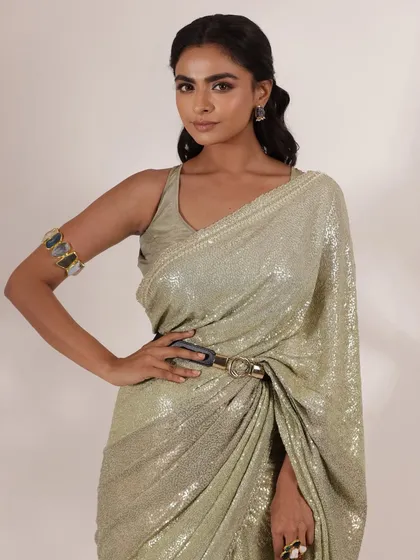 To give this sequined saree a modern twist, I added a stylish belt and an arm cuff. This is a great example of how I use accessories to redefine a traditional silhouette for a more contemporary feel.