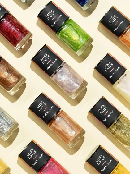 This satisfying grid layout showcases a range of shimmery nail polishes. The hard light catches the glitter in each bottle, making them sparkle and creating a mesmerizing, tile-like effect.
