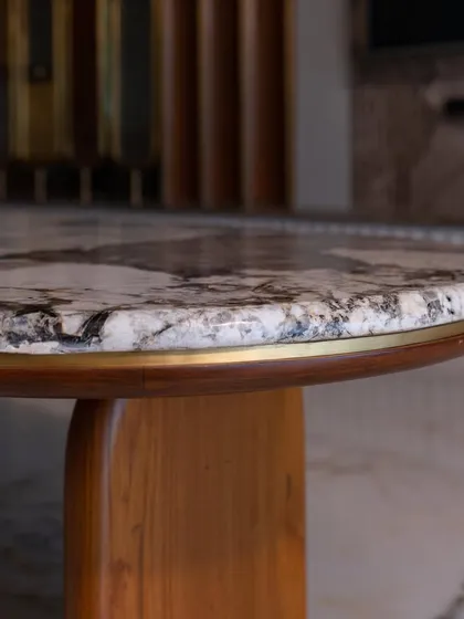 A close-up of the coffee table's edge, showing the beautiful grain of the wood and the brass inlay bordering the marble.